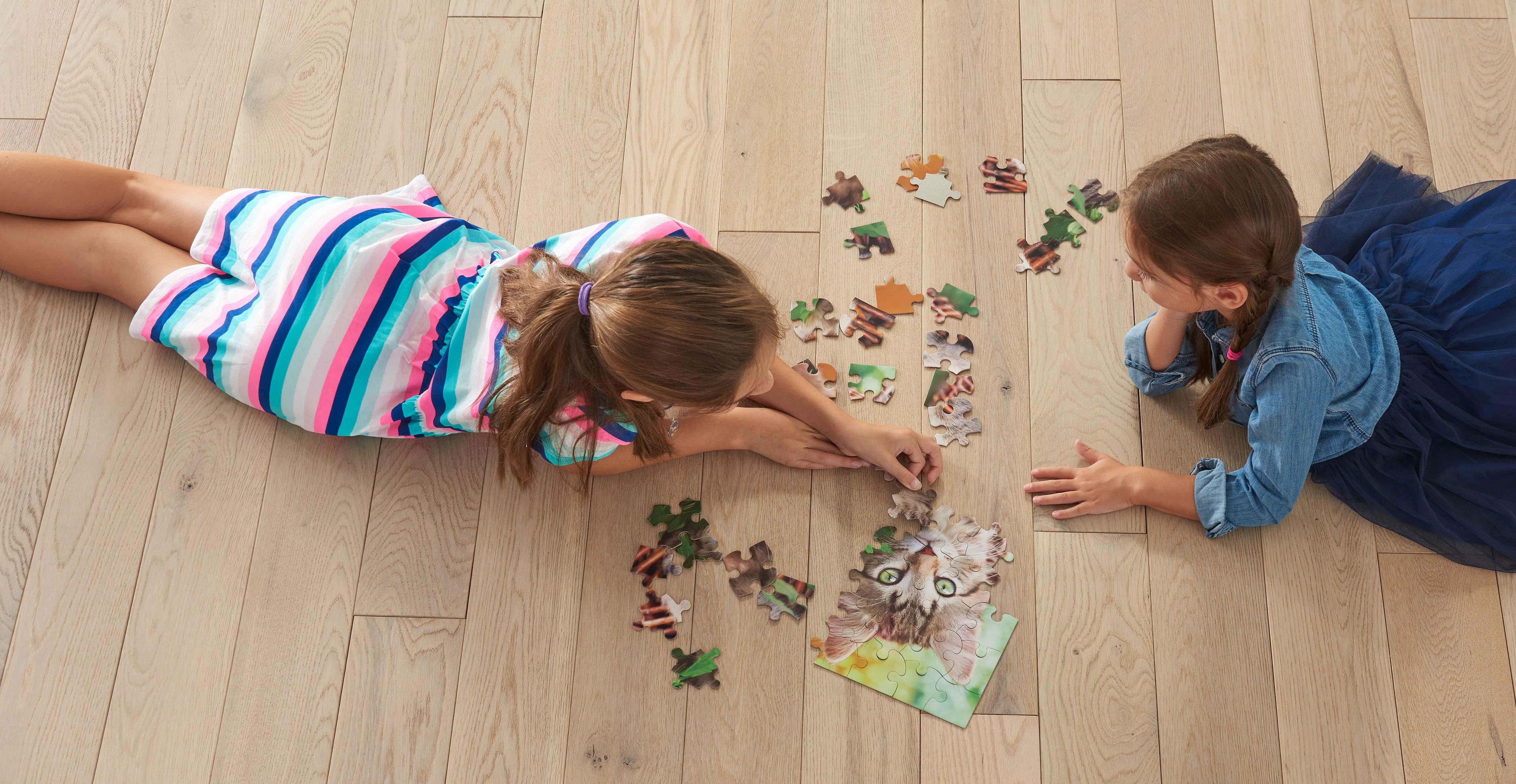 Children playing with a puzzle on hardwood floor