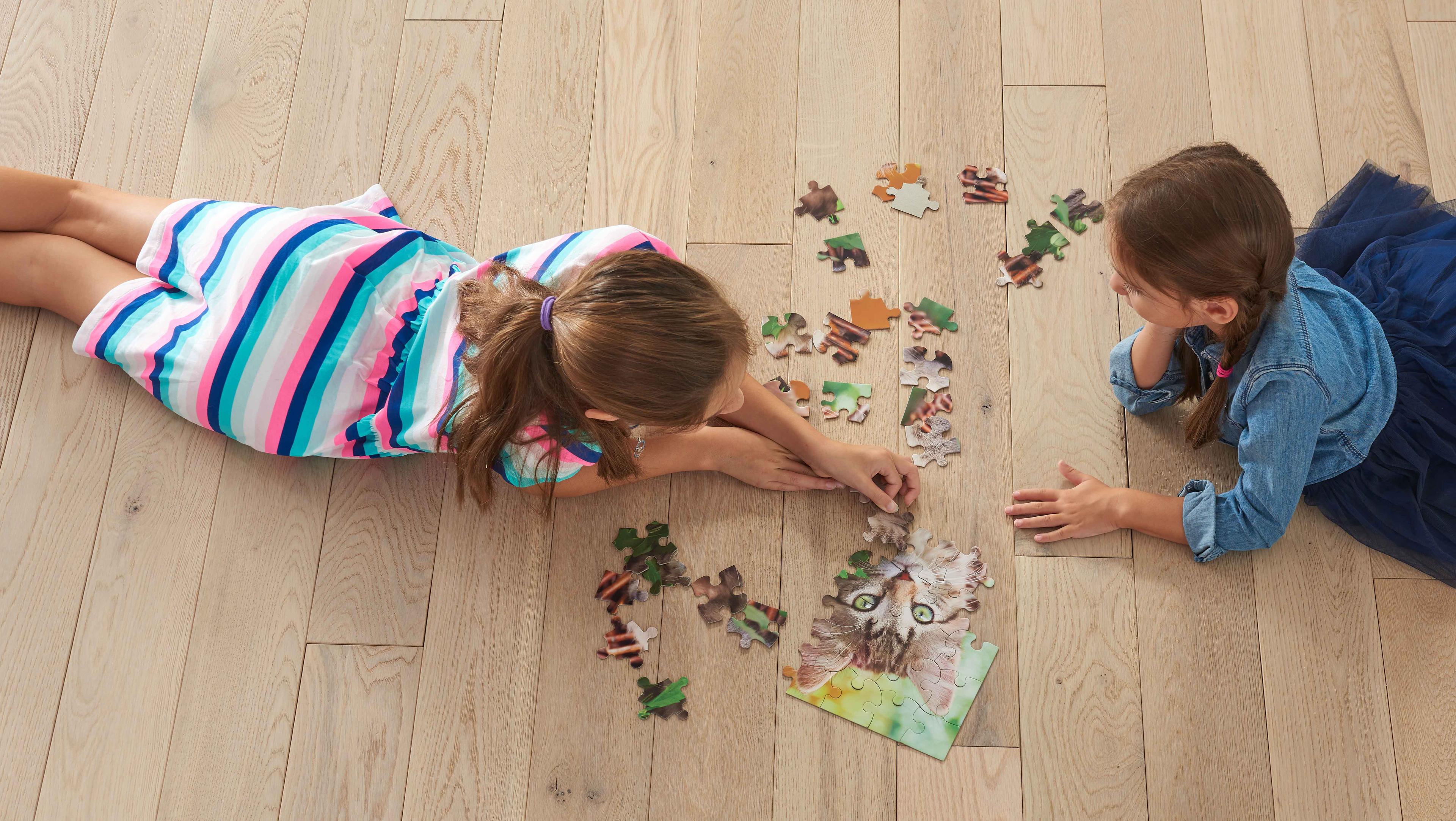 Children playing with a puzzle on hardwood floor