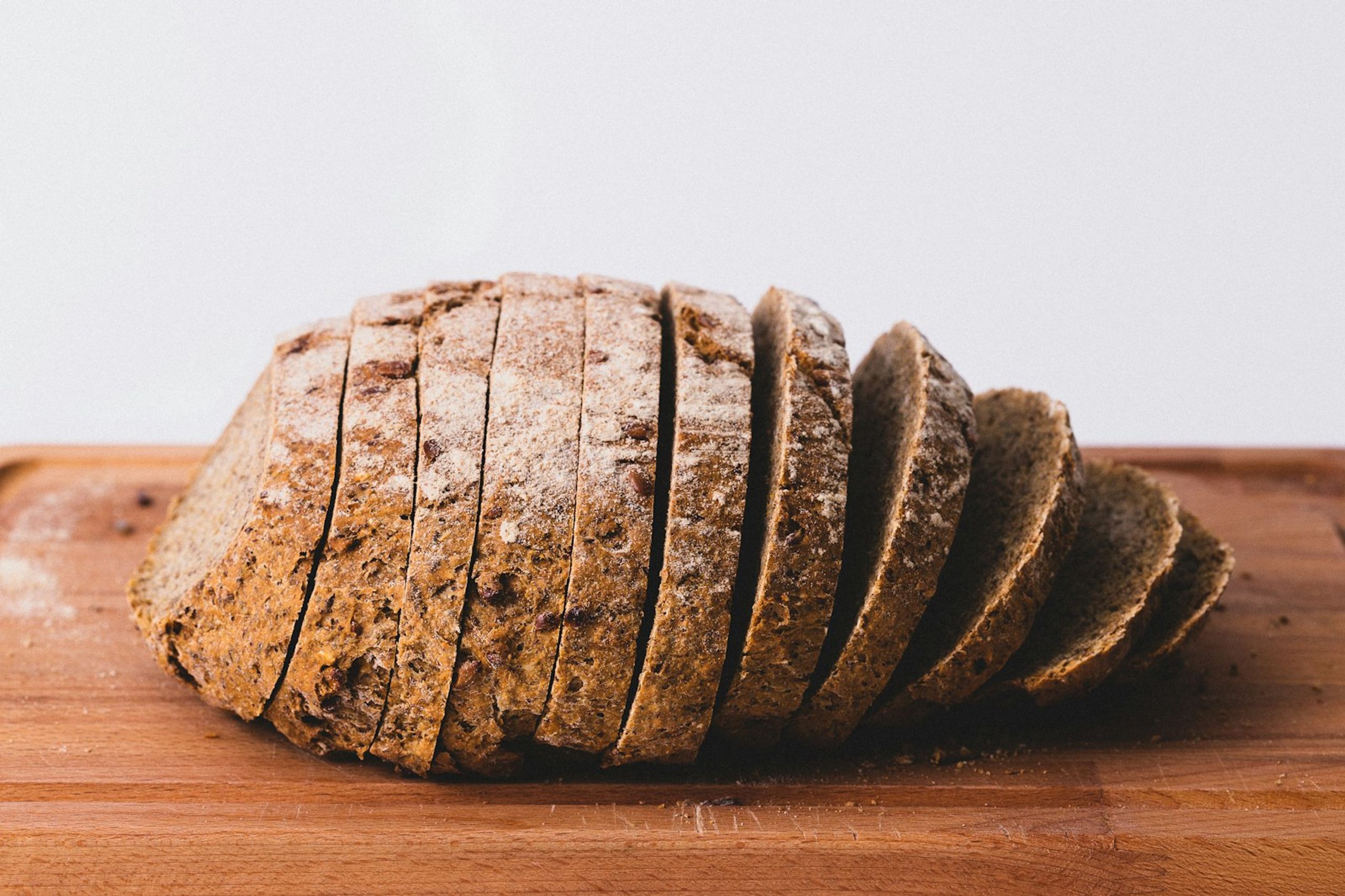 Pagnotta di pane integrale affettata su un tagliere di legno