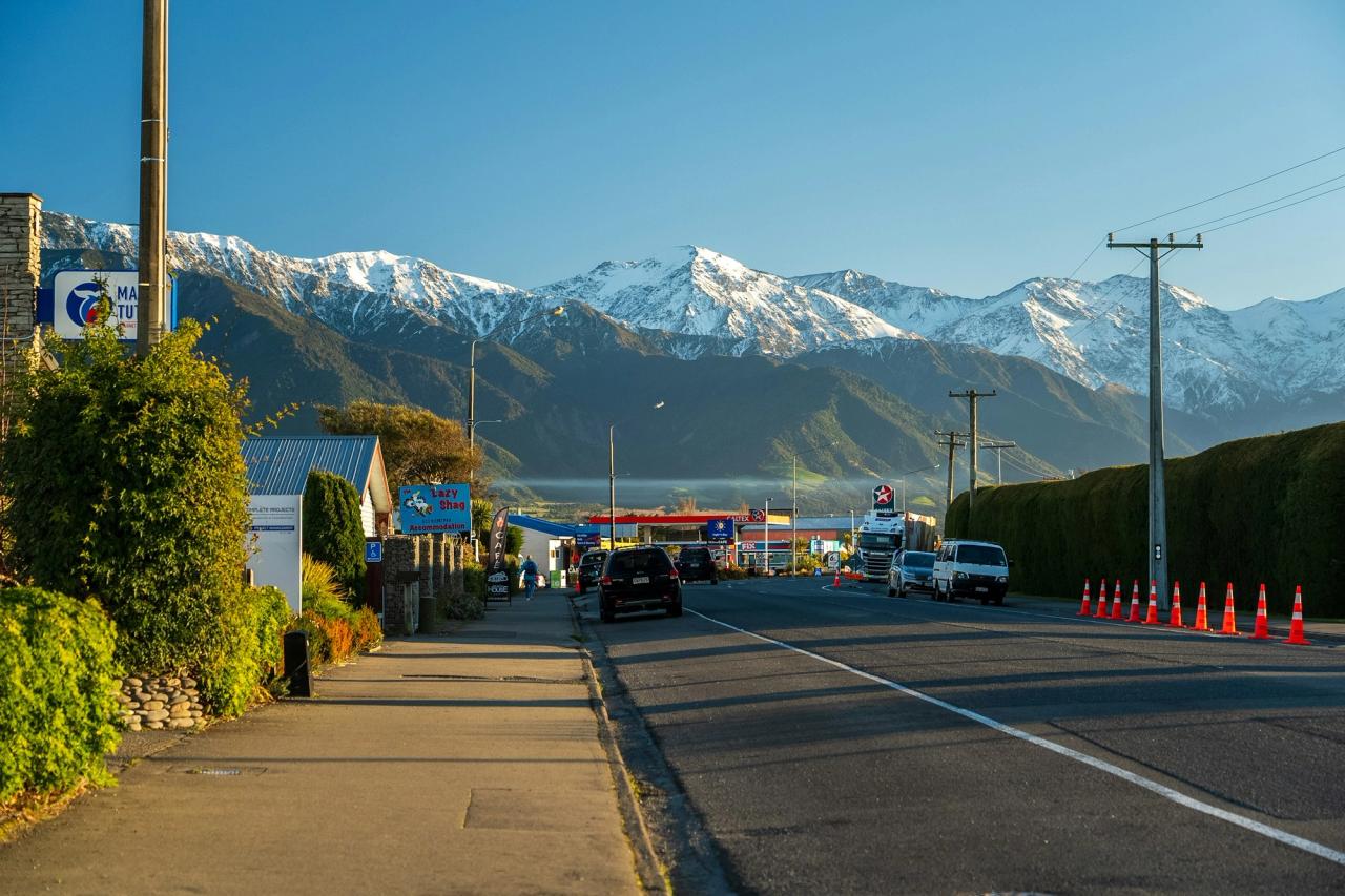 Highway through a South Island town with a line of road cones and snow-capped mountains behind