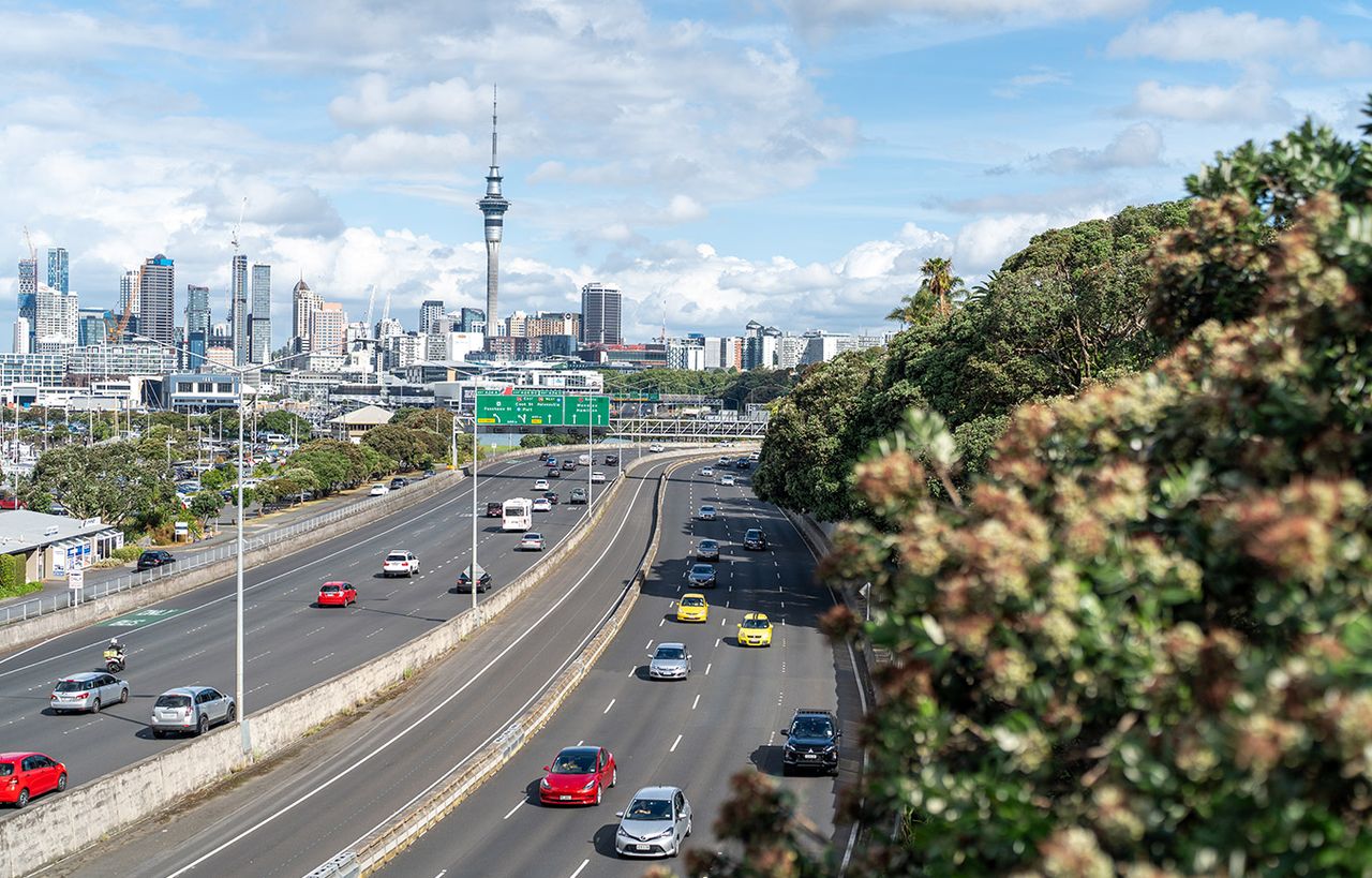 Auckland motorway traffic with the city skyline and Sky Tower behind
