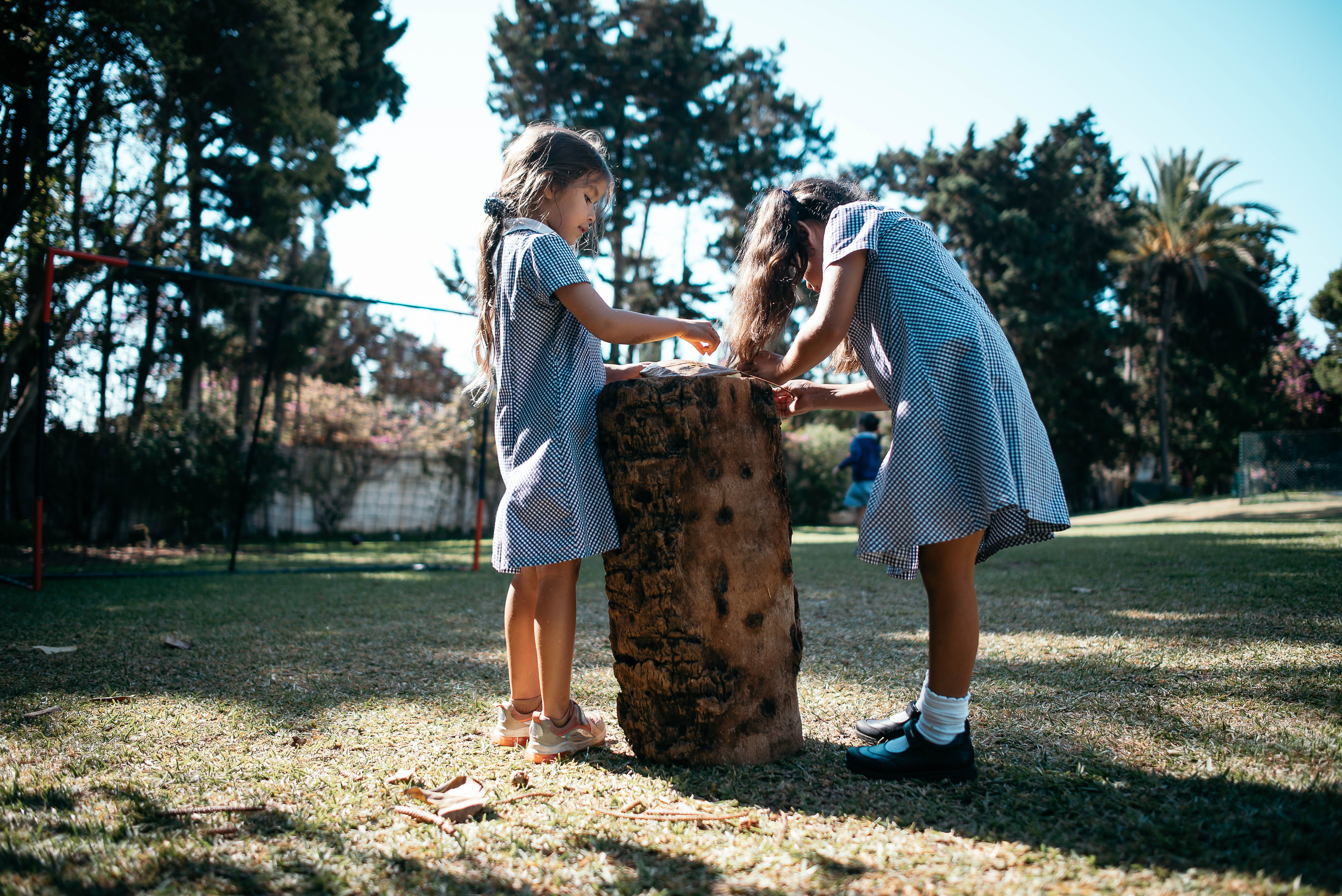 two small girls playing together on log outside