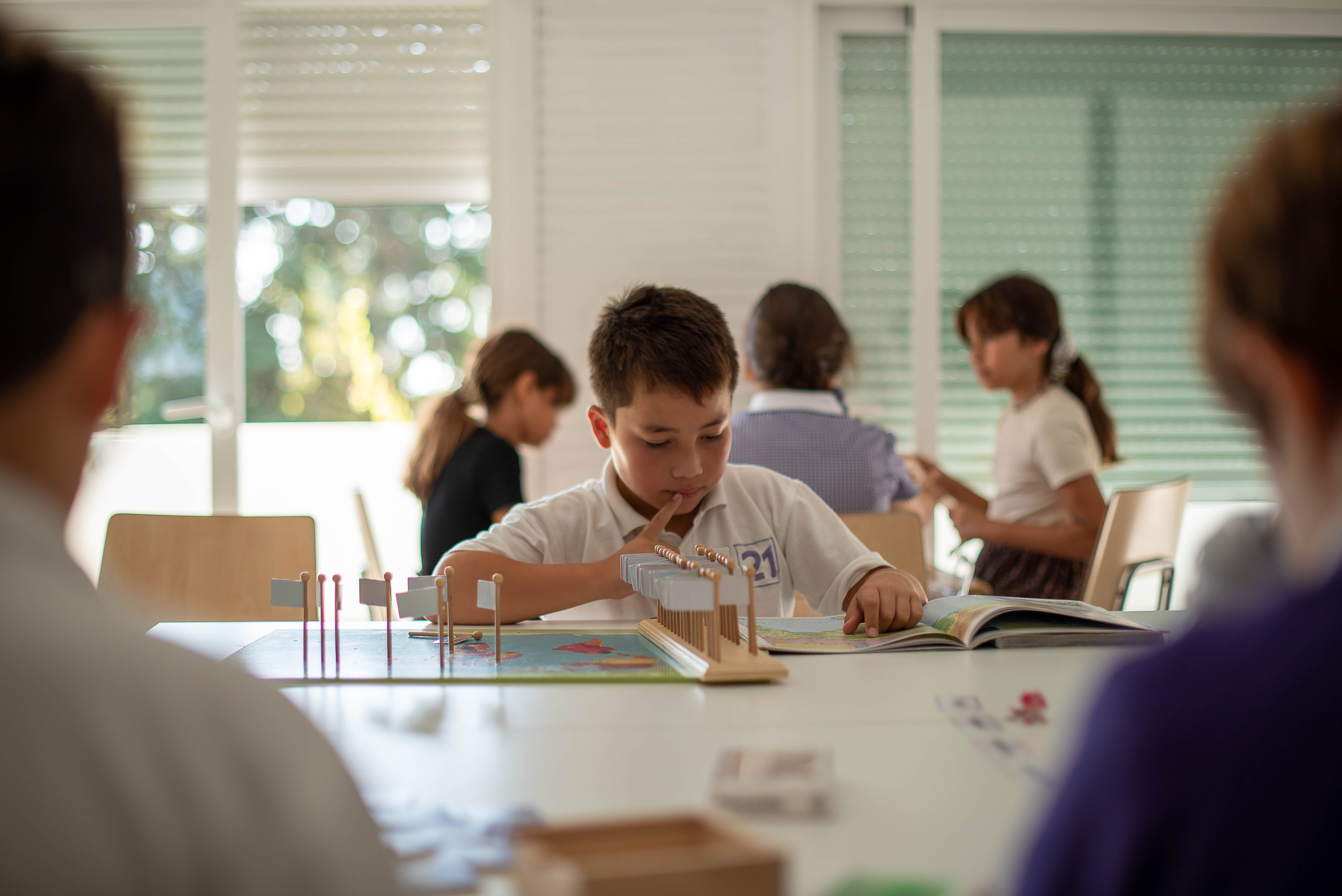 small boy looking as book in Montessori school