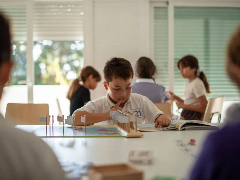 small boy looking as book in Montessori school