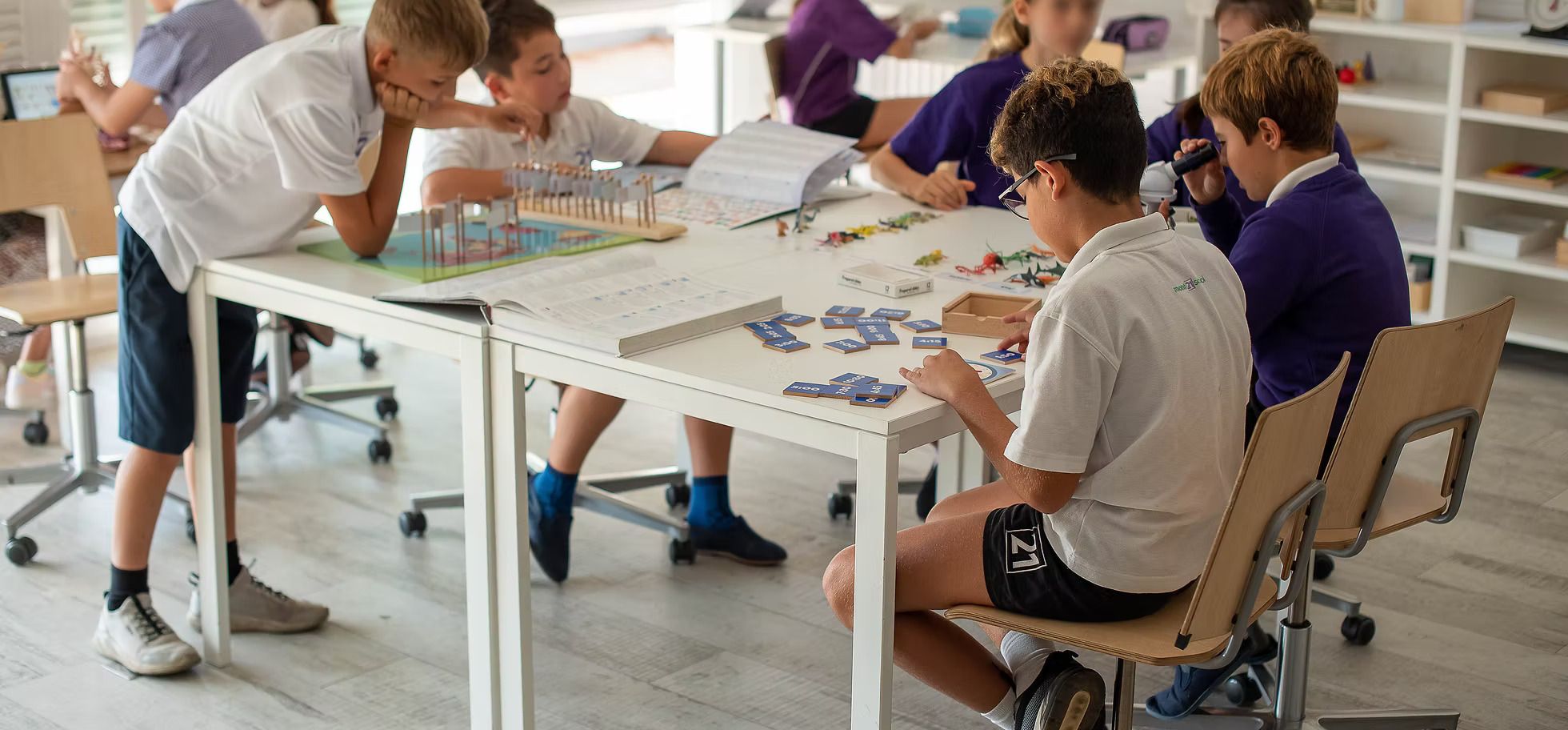 Children sat doing practical learning at a classroom table in Mont21 school