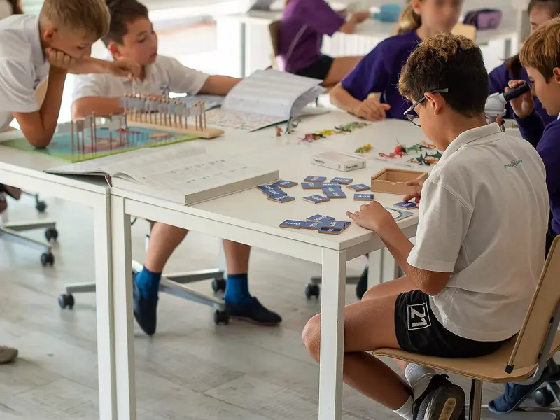 Children sat doing practical learning at a classroom table in Mont21 school