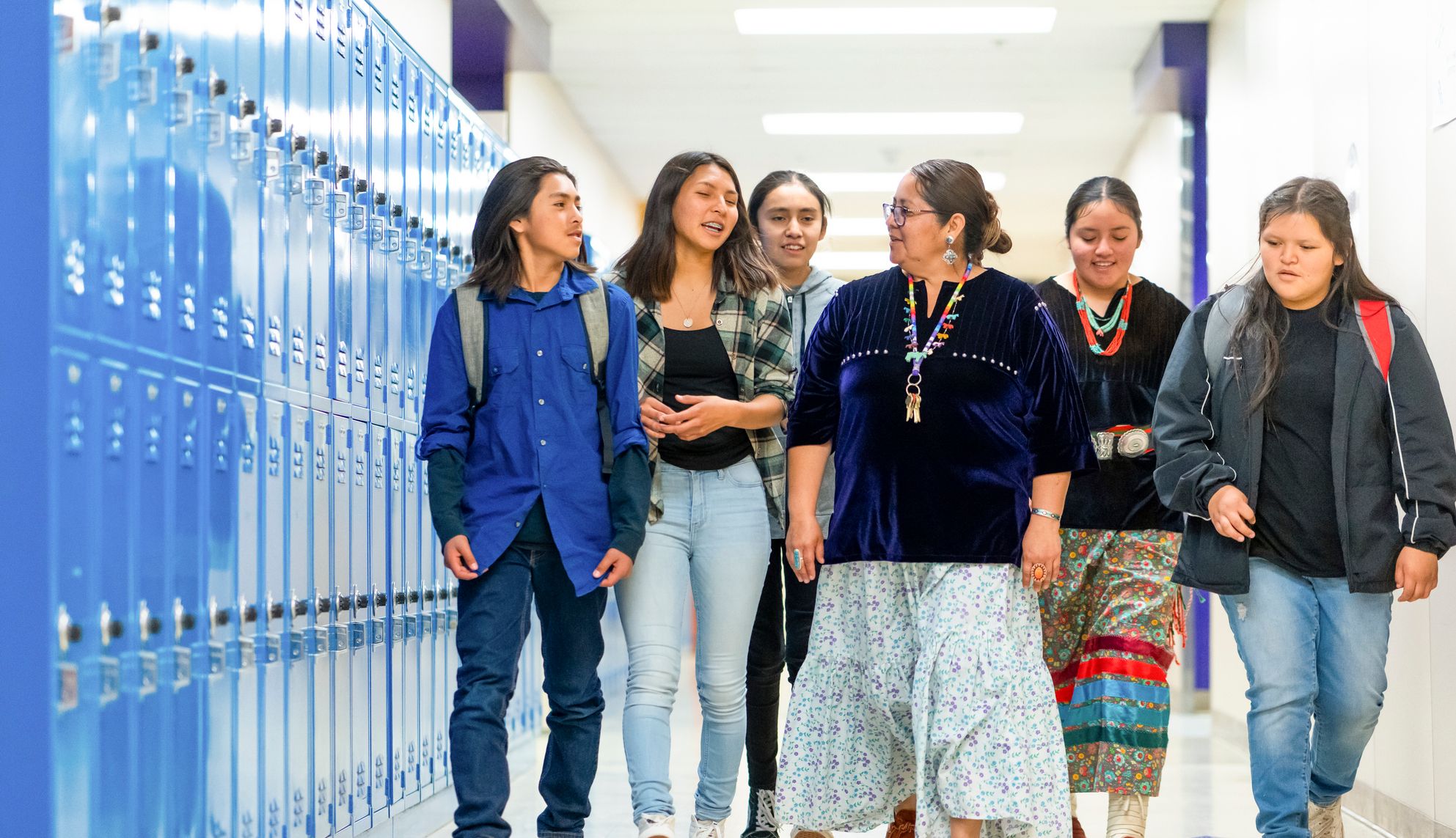 A teacher walking through a school hallway with a group of students