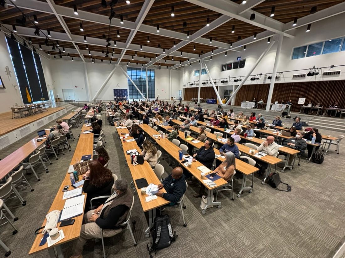 Nonprofit staff seated at long rows of tables during a large Groundworks New Mexico training session