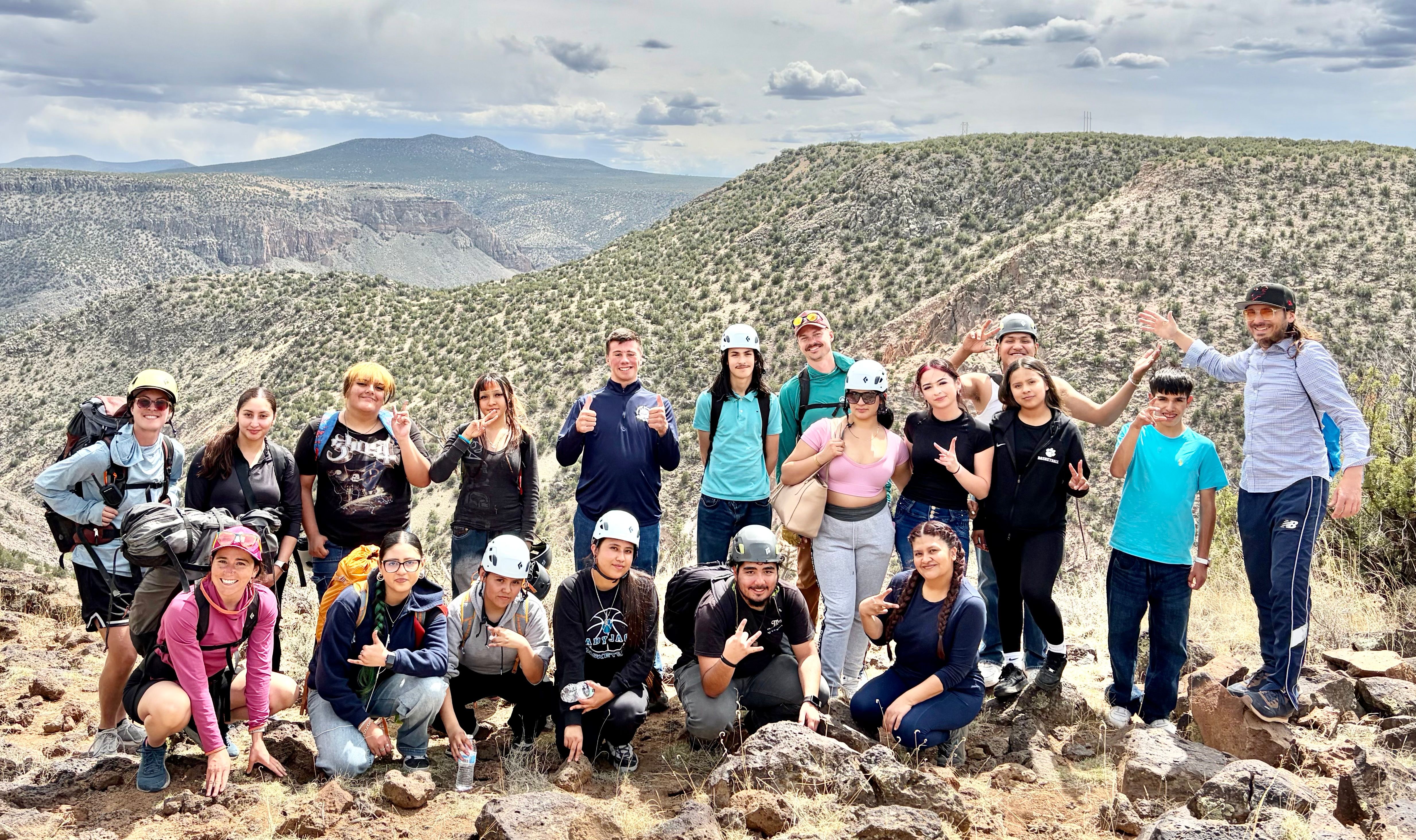A group of students and staff posing on a hilltop overlooking a New Mexico canyon