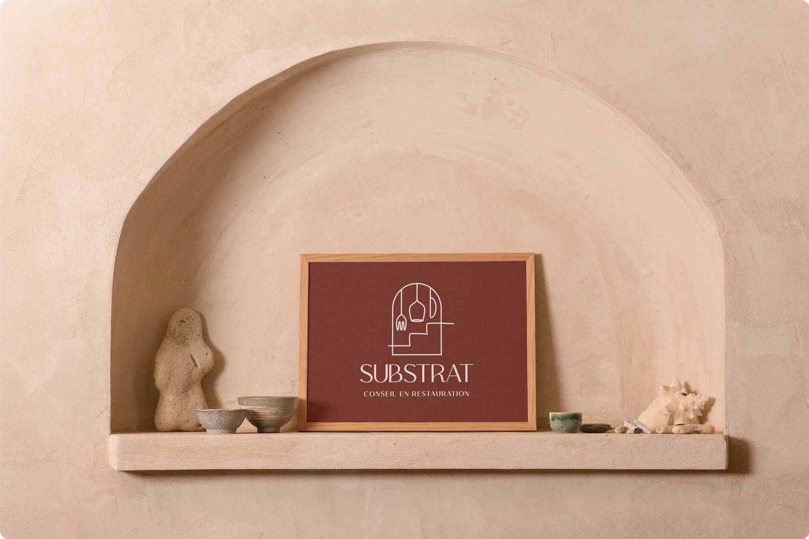 Logo de Substrat dans un cadre en bois à l'intérieur d'une arche murale avec des élements de décorations autour.