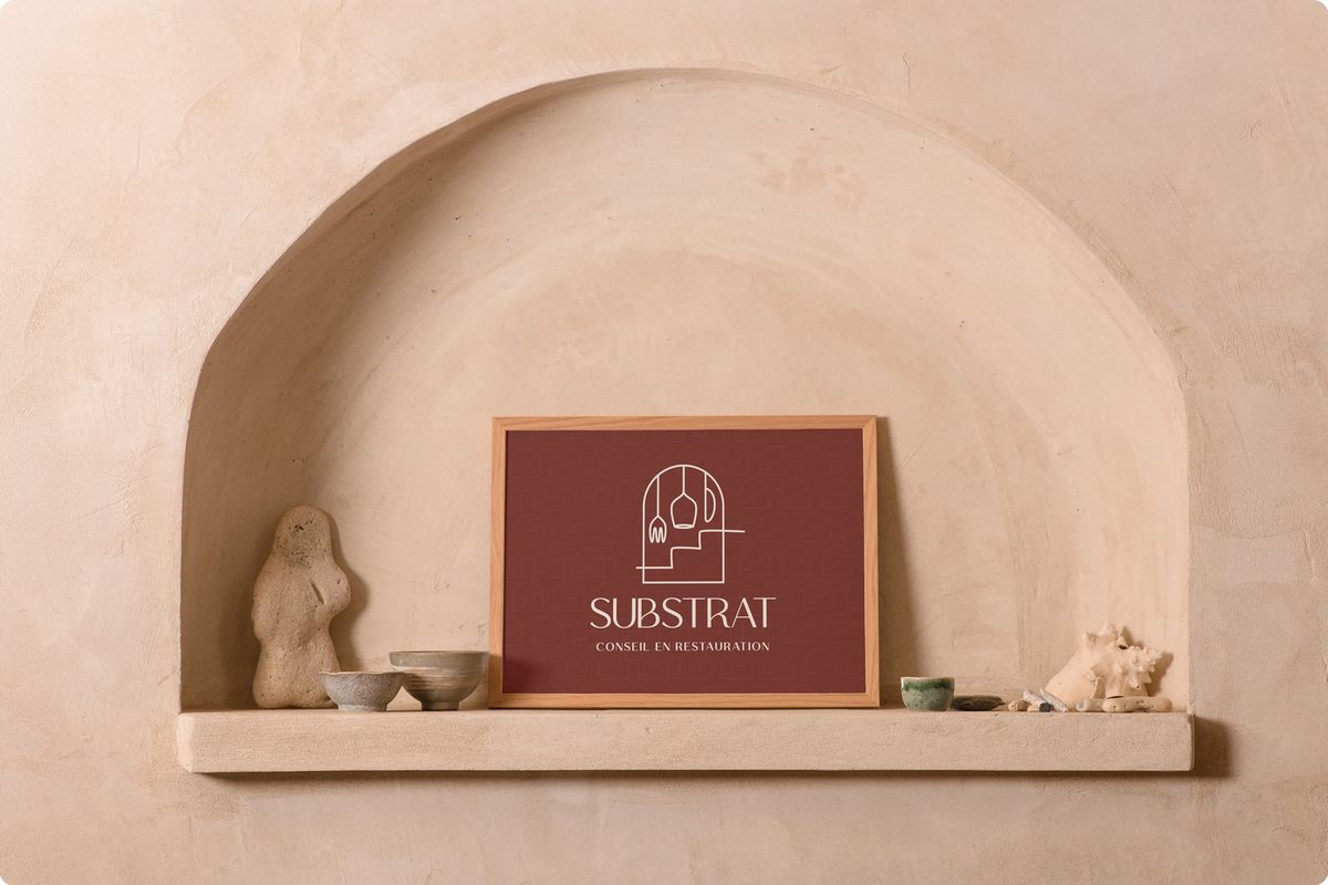 Logo de Substrat dans un cadre en bois à l'intérieur d'une arche murale avec des élements de décorations autour.