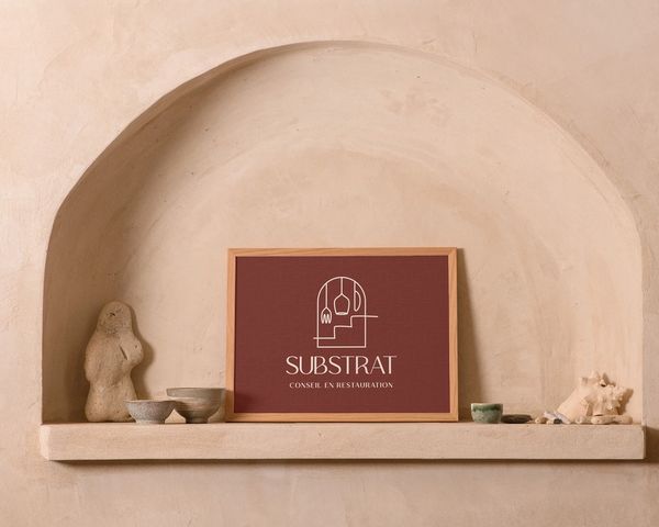 Logo de Substrat dans un cadre en bois à l'intérieur d'une arche murale avec des élements de décorations autour.