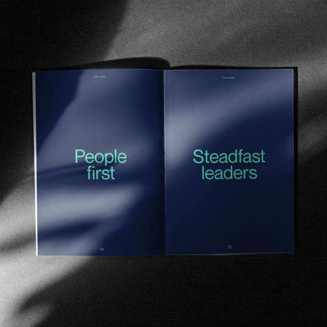 An open magazine with the text that reads People first on a blue background taking up the entire first page and text "Steadfast leaders" on blue background taking up the entire second page.