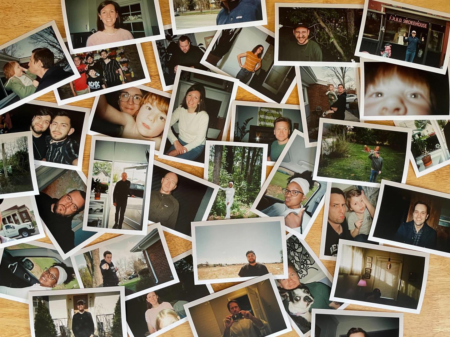A collection of scattered polaroid photographs of Bullhorn team members and their families on a wood tabletop.