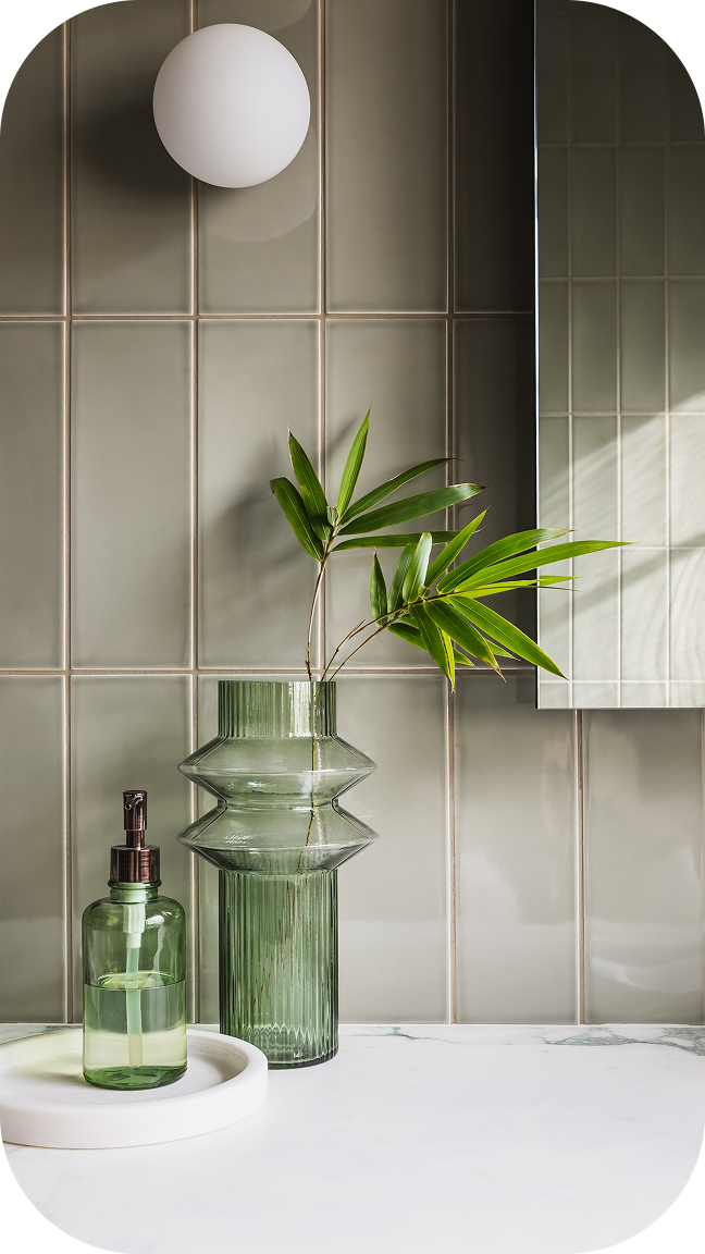 Modern minimalist interior with mirror, decorative glass vases, and plants on tiled wall