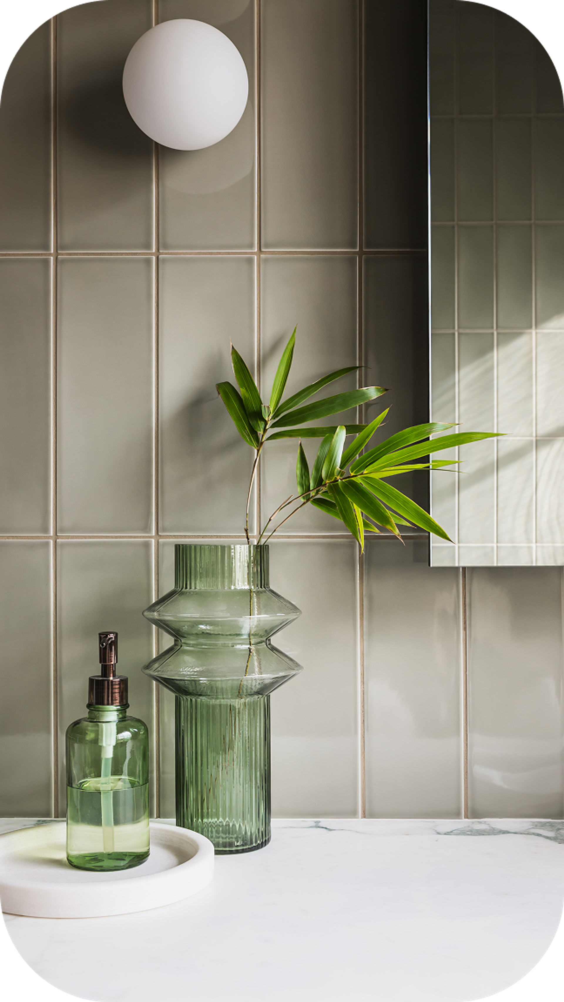 Modern minimalist interior with mirror, decorative glass vases, and plants on tiled wall