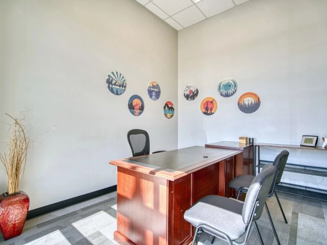 Furnished private office with executive desk and circular mountain artwork at Leaf Coworking, Firestone, CO