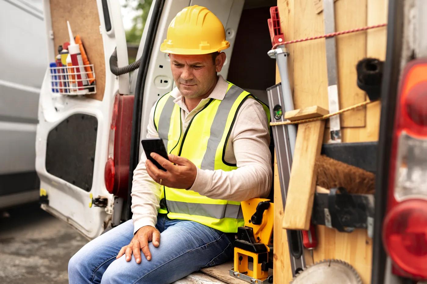 A tradesperson finishing paperwork on a phone beside their van