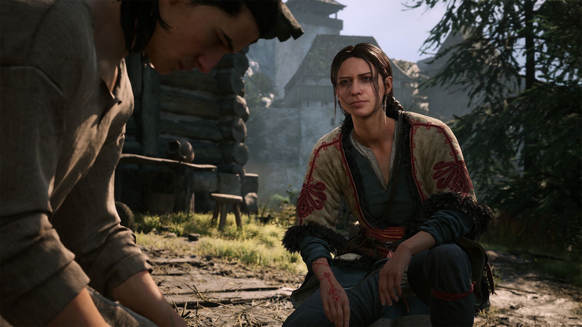A woman kneels and speaks with another person in a village