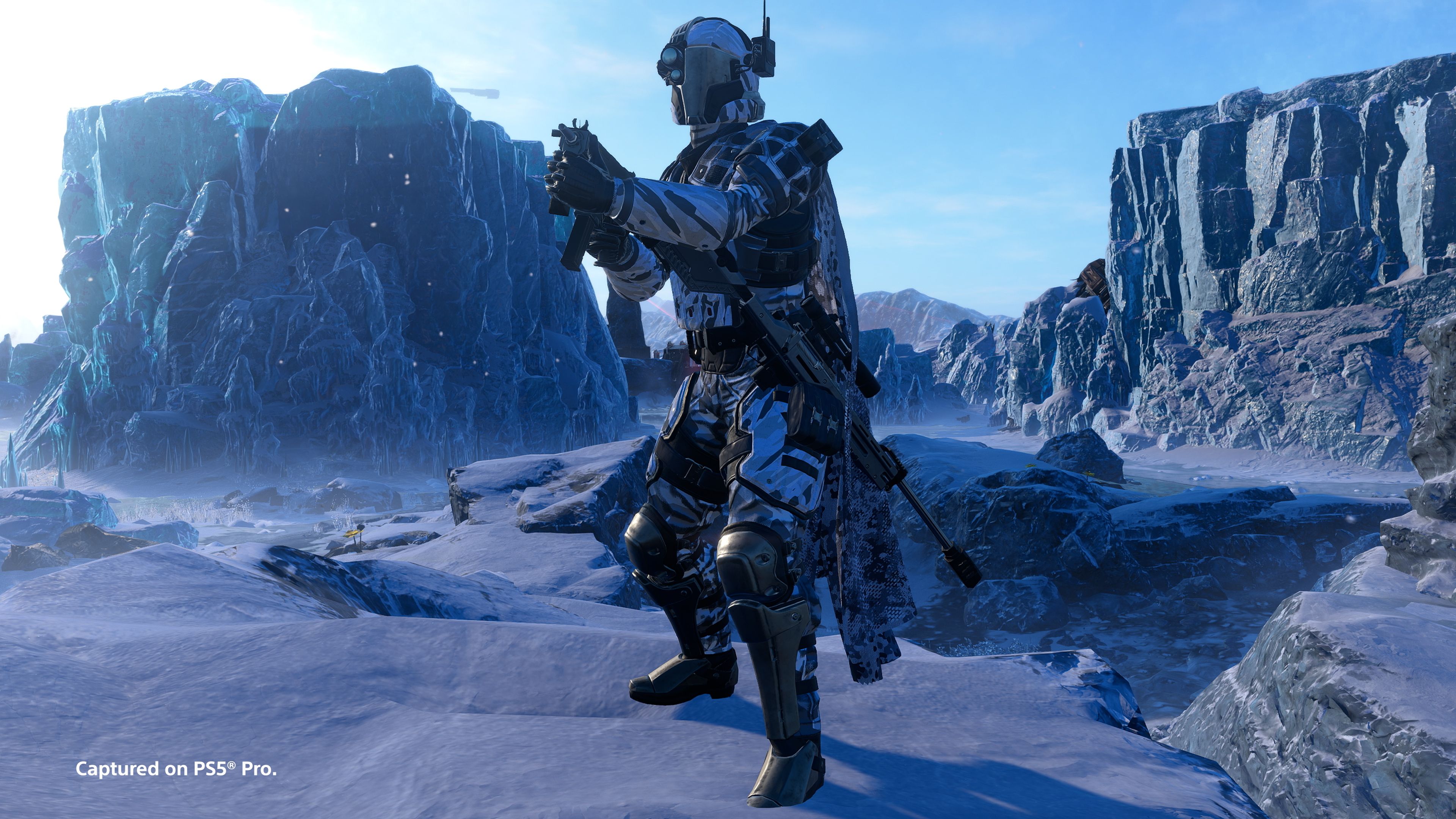 A Helldiver in blue camouflage holds a machine pistol beside icy cliffs.
