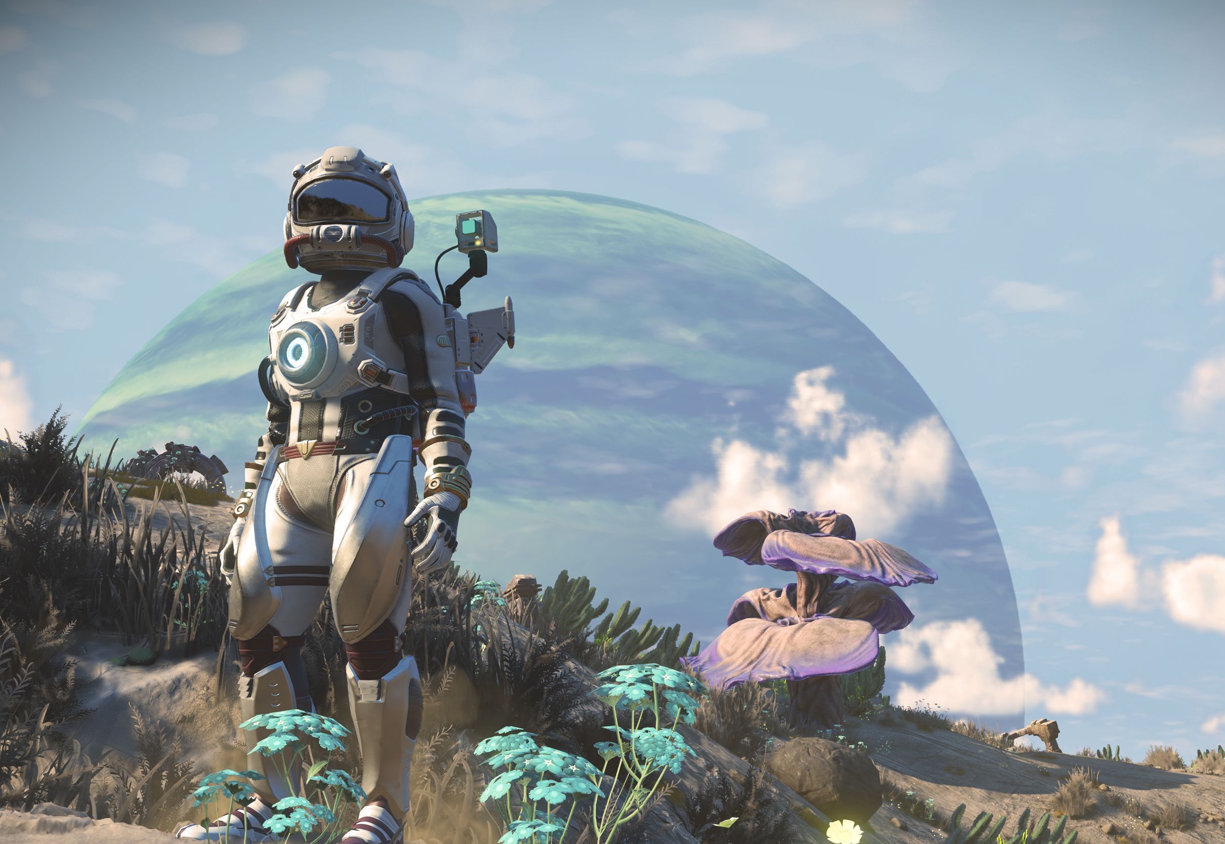 A suited No Man's Sky traveler stands beside alien plants beneath a large planet in official iOS announcement artwork.