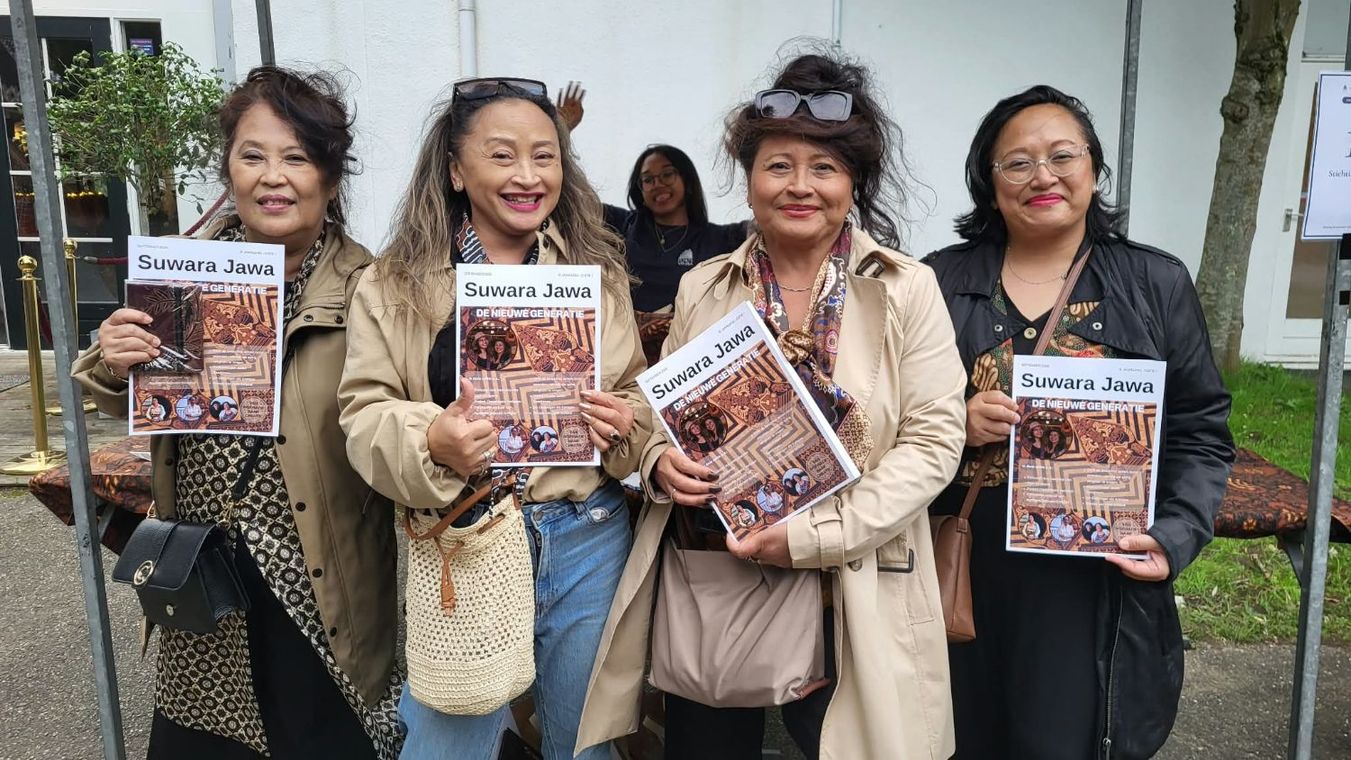 Vier vrouwen houden ieder een exemplaar van de eerste editie omhoog, buiten bij de ingang