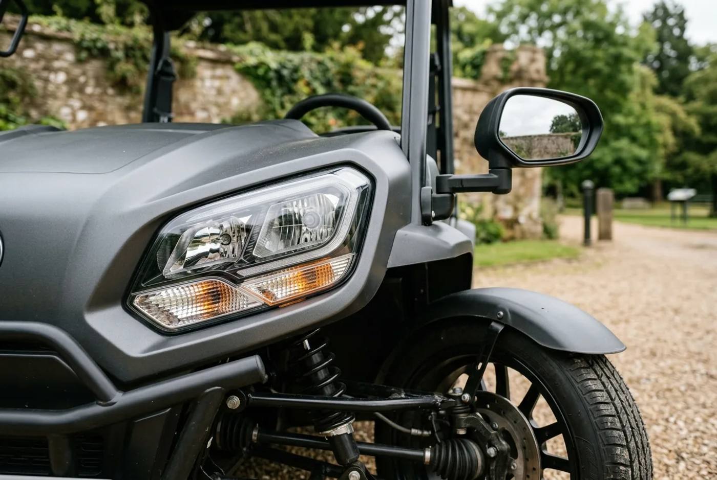 Close-up of an electric buggy front showing road-type headlights, an amber indicator and a wing mirror