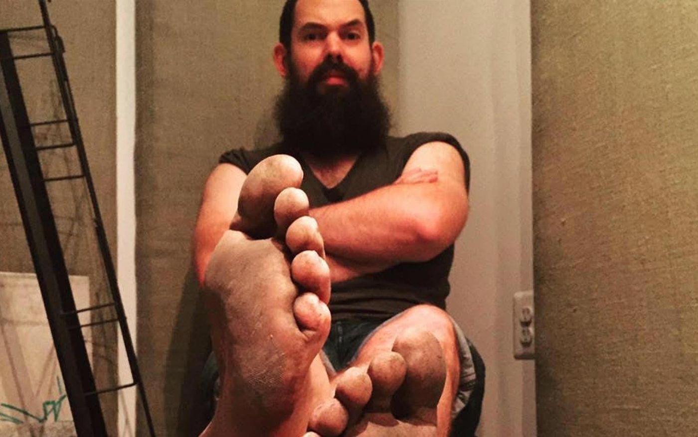 Foley artist Matt Davies sitting with his dirty bare feet raised toward the camera