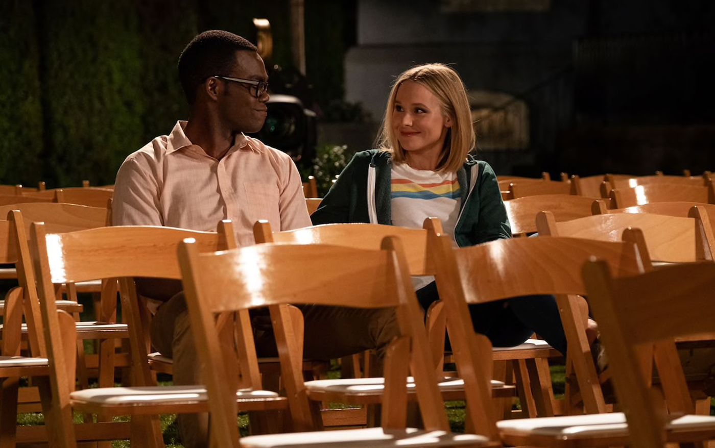 Chidi (William Jackson Harper) and Eleanor (Kristen Bell) sitting among empty folding chairs in The Good Place