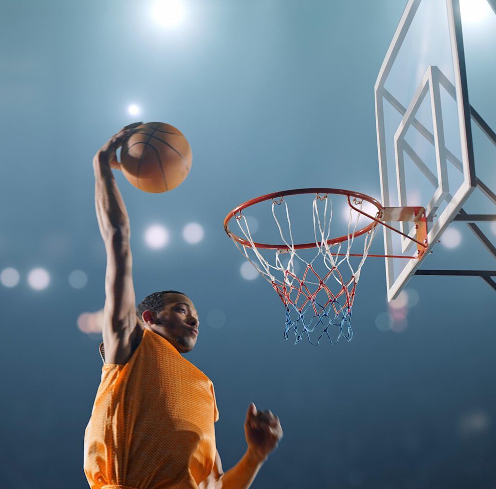 Basketball player leaping for a dunk under arena lights