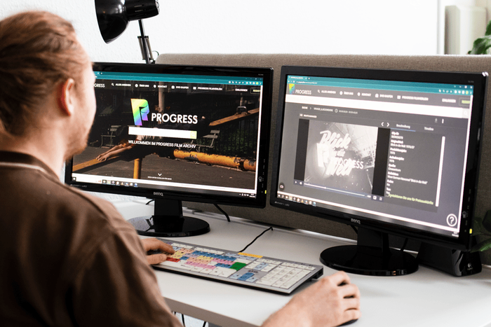 Archivist browsing the PROGRESS film archive website on two monitors