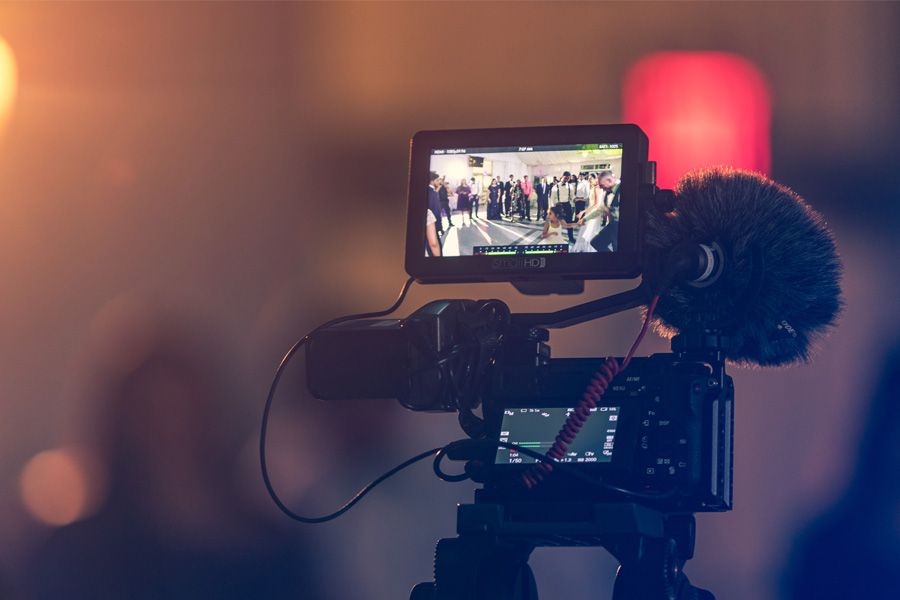 Camera on a tripod with an external monitor and shotgun mic filming an event