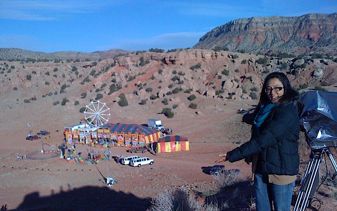 Ester Kim on a desert hillside above a carnival set on the Passion Play (2010) location