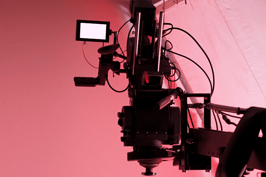 Cinema camera rig on a crane against a red-lit background