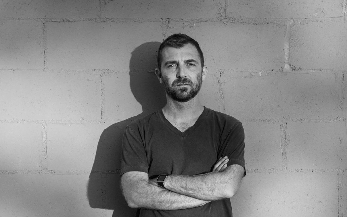 Black and white portrait of sound designer Joseph Fraioli, arms crossed against a cinder block wall