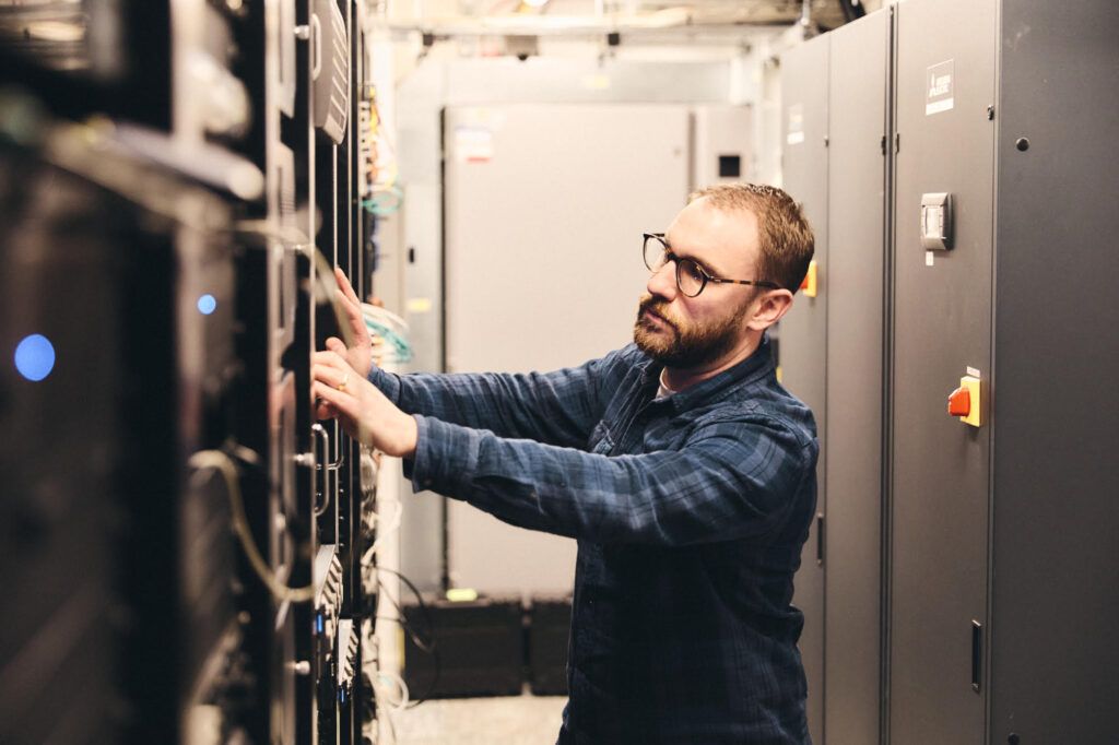 Engineer working on server racks in the machine room of a Central London post facility