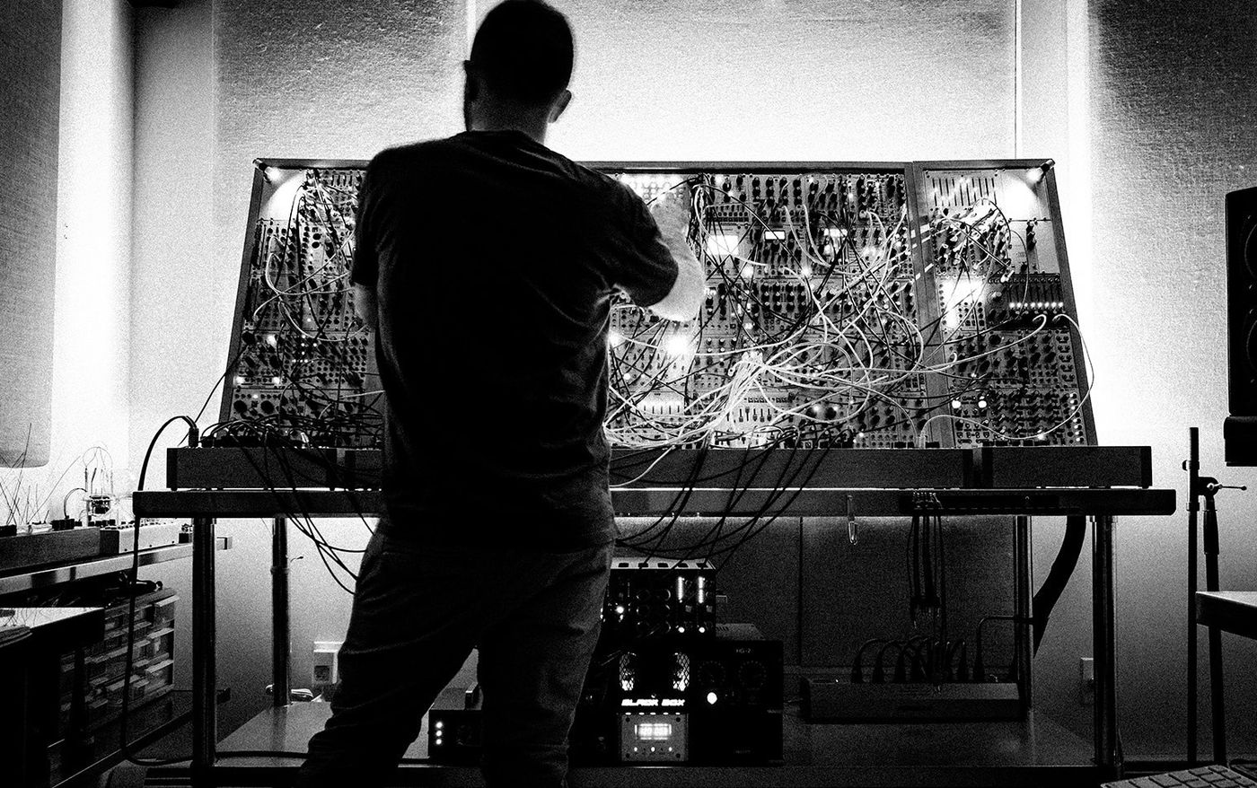 Joseph Fraioli patching cables on his large modular synthesizer, in black and white