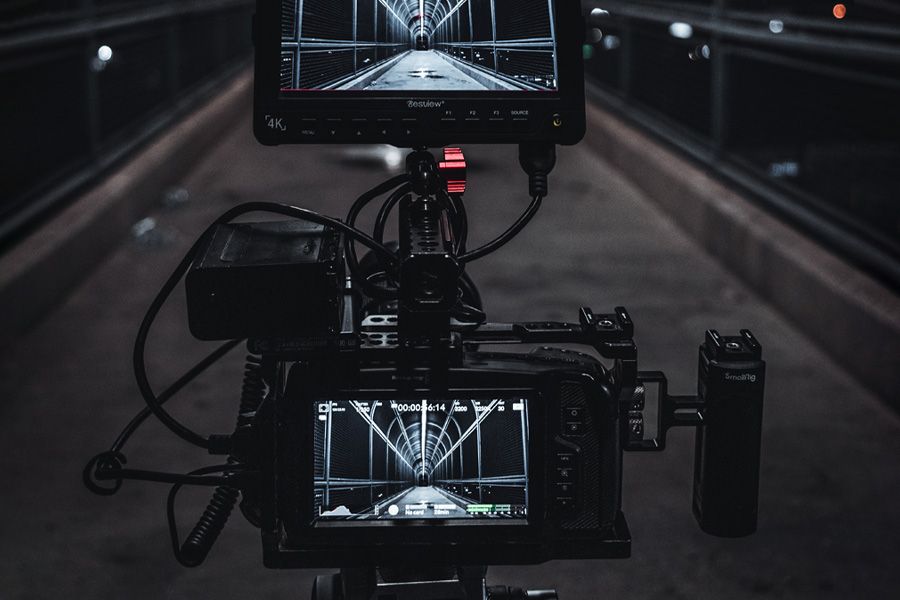 Cinema camera rig with an external monitor filming a lit pedestrian bridge at night
