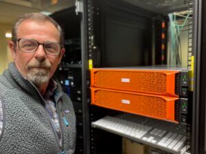 Michael Svirsky, Post Production Manager at Roku Inc., beside orange EditShare storage units in a server rack