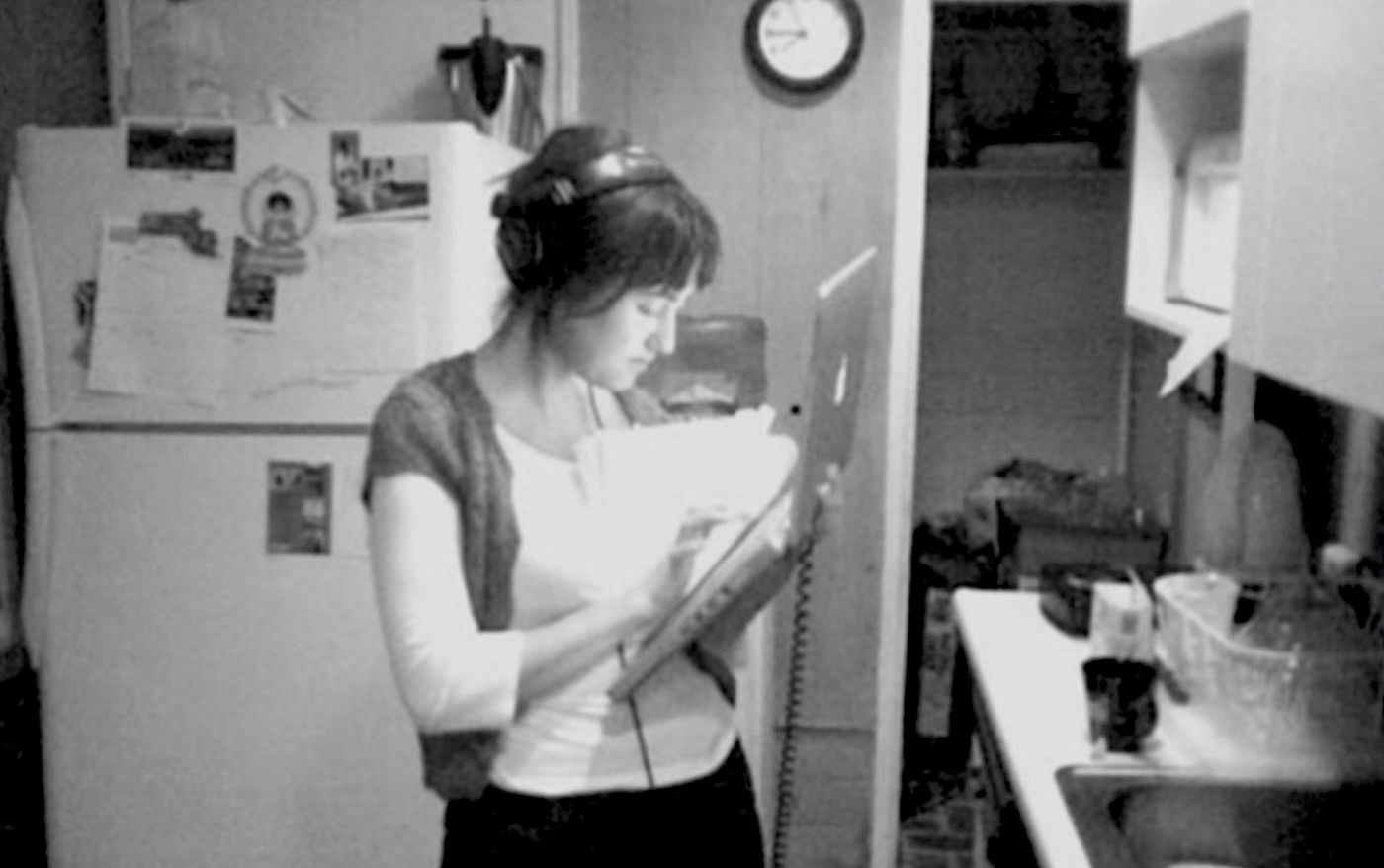 Lindsay Utz wearing headphones and reviewing papers in the kitchen at the GOOD house in Los Angeles