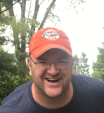 Headshot of webinar speaker Grant Carroll, Director of Workflow Design, wearing an orange cap