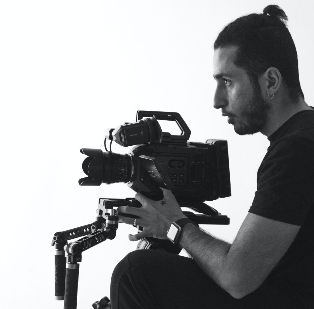 Camera operator in profile holding a Blackmagic cinema camera on a shoulder rig