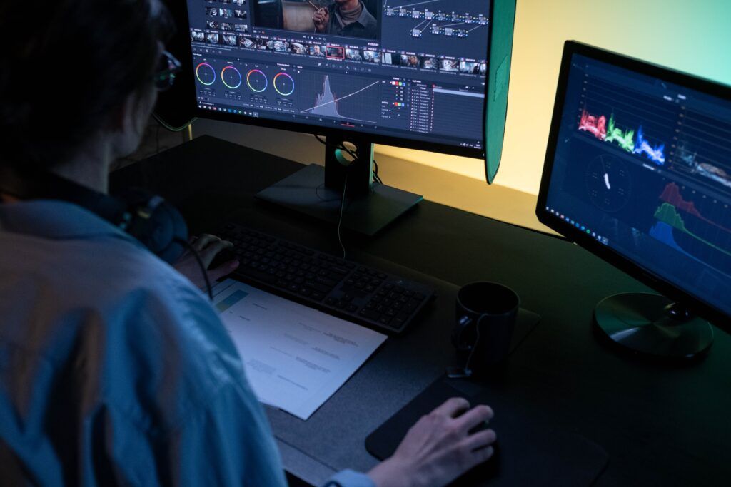 Colorist grading footage in DaVinci Resolve across two monitors with color wheels and scopes
