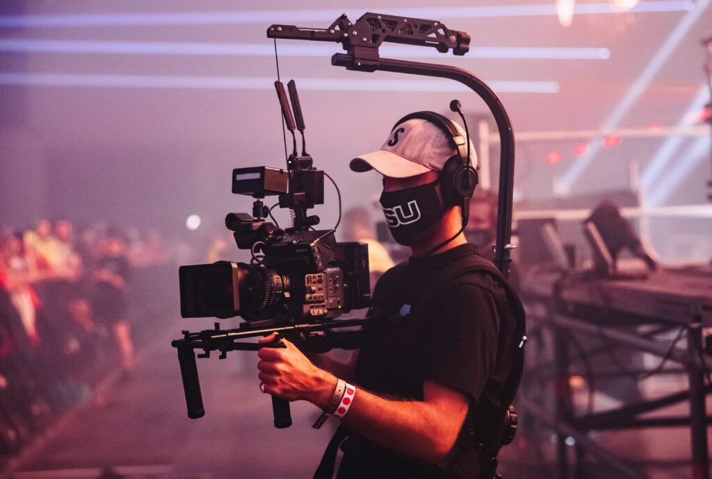 Camera operator filming a live event with a cinema camera on a stabilizer arm