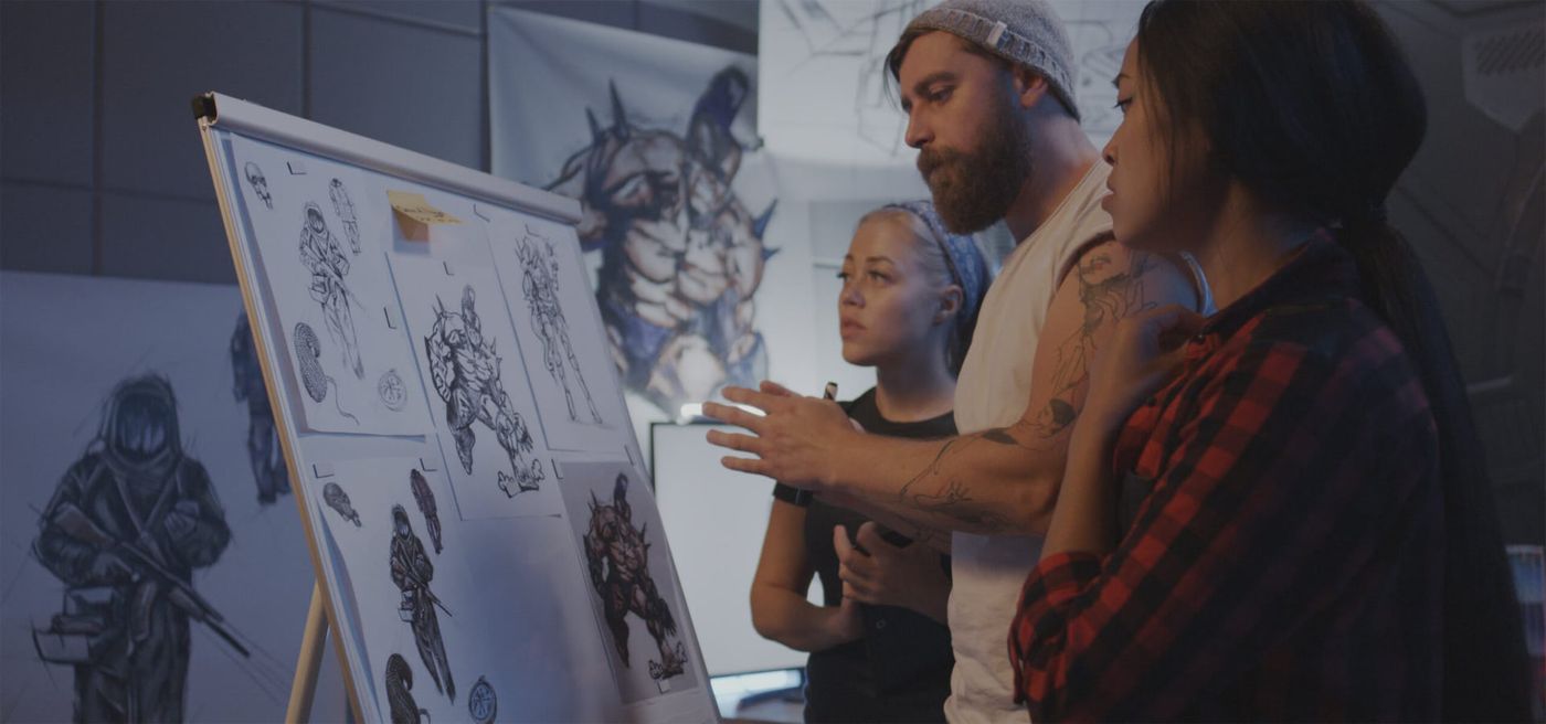 Game artists reviewing character concept sketches on a board