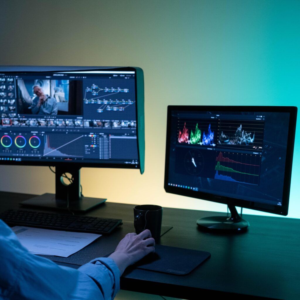 Colorist working in DaVinci Resolve with color wheels on one monitor and scopes on a second