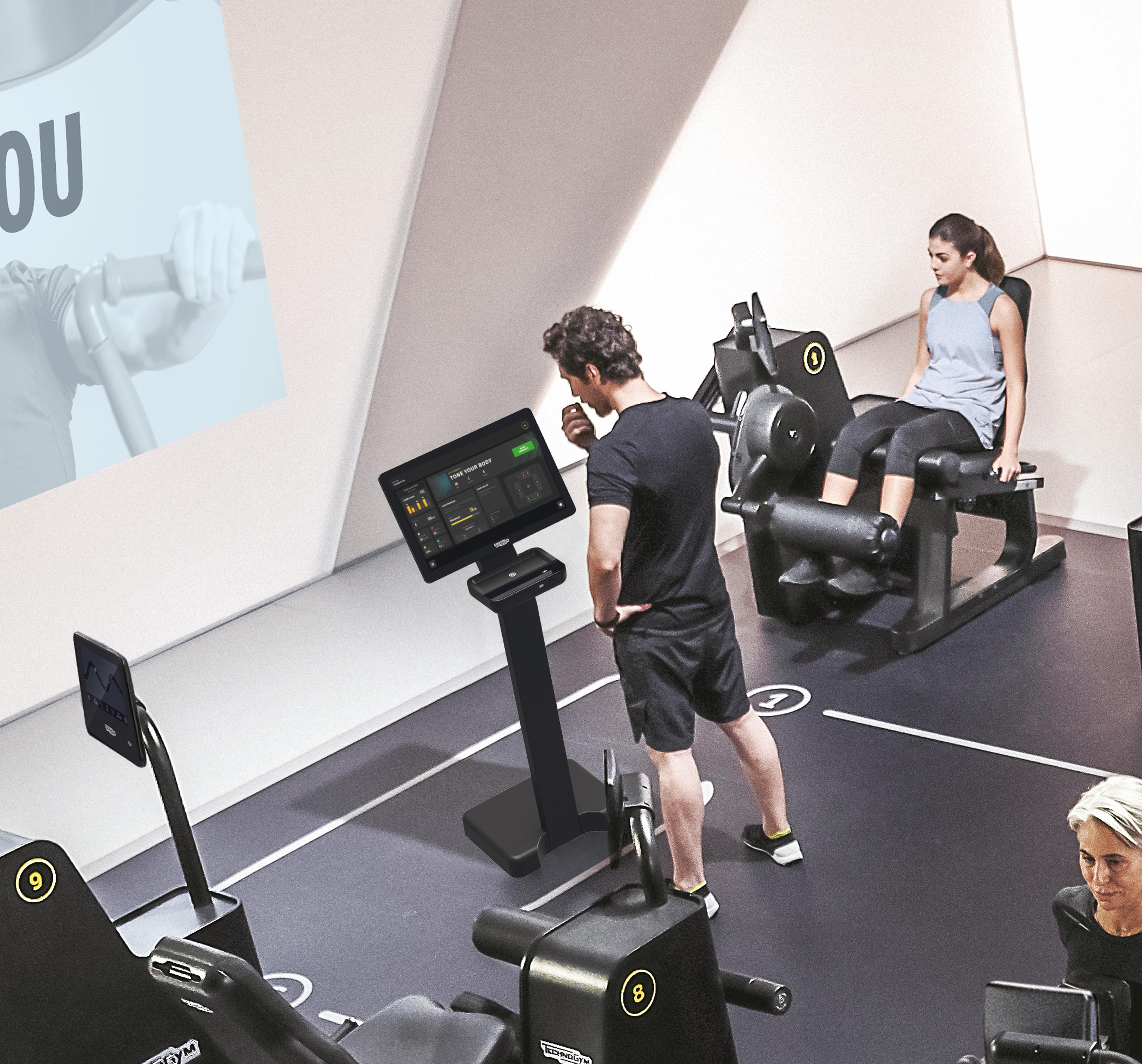 Personen trainieren in einem modernen Fitnessstudio mit digitalen Trainingsgeräten und Bildschirmen