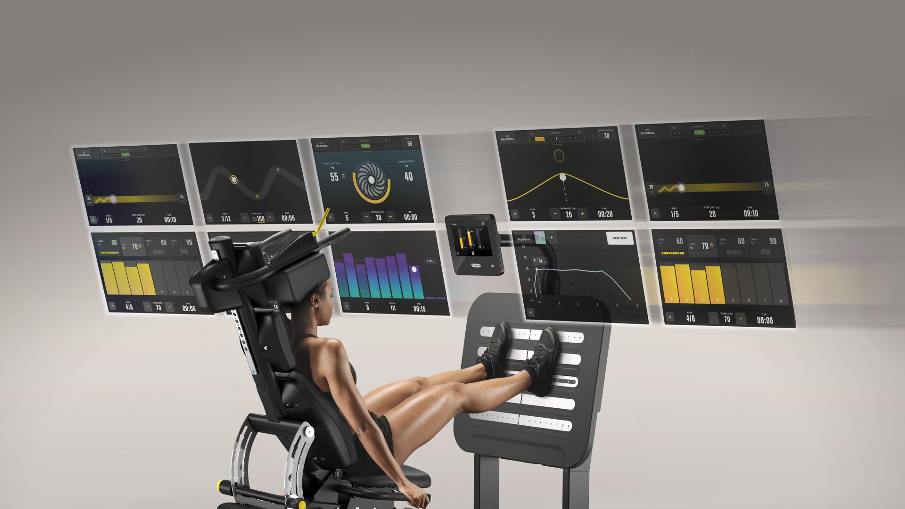 Eine Person trainiert an einer modernen Fitnessstation mit mehreren digitalen Bildschirmen, die Leistungsdaten anzeigen.