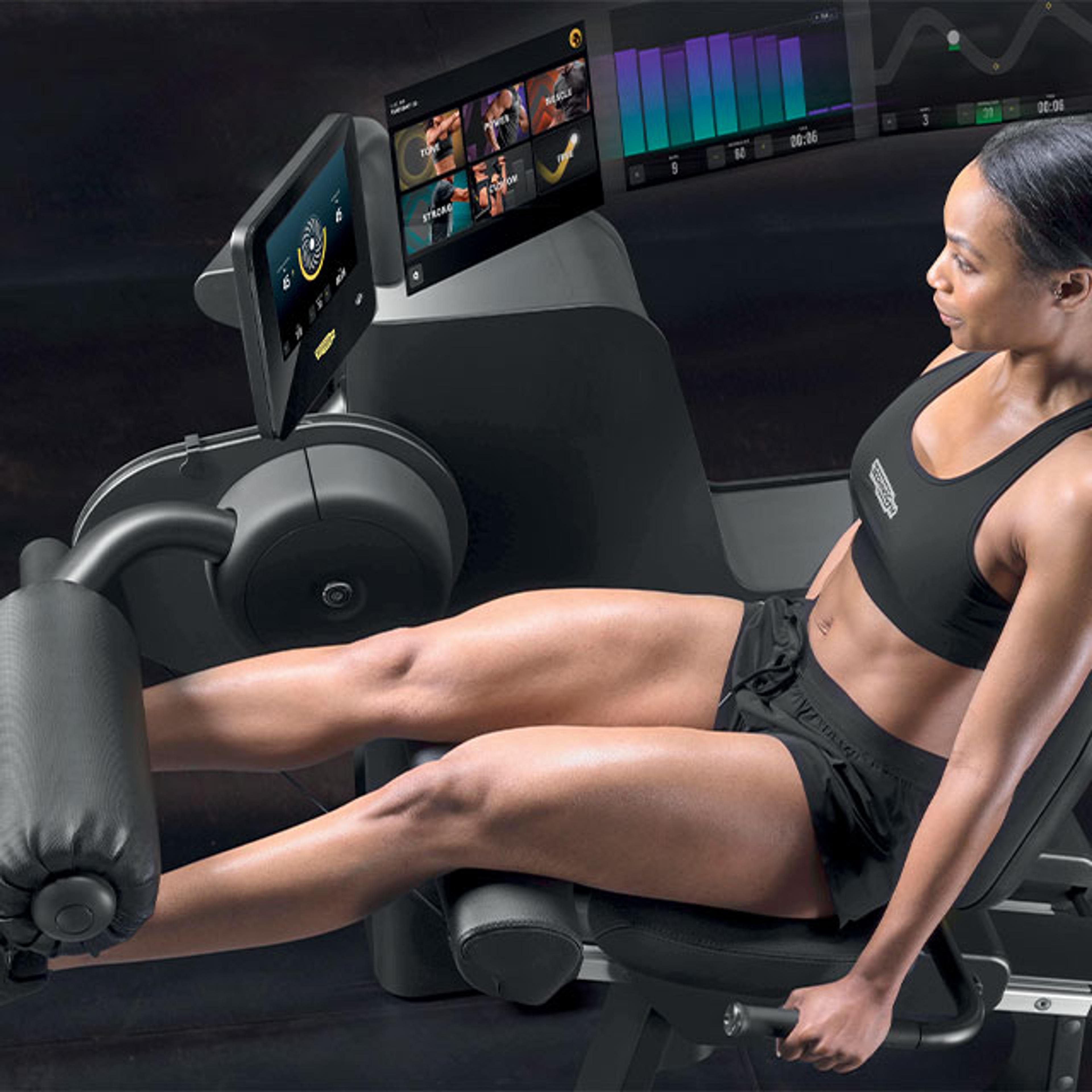 Eine Frau in Sportkleidung trainiert an einem modernen Fitnessgerät im Fitnessstudio