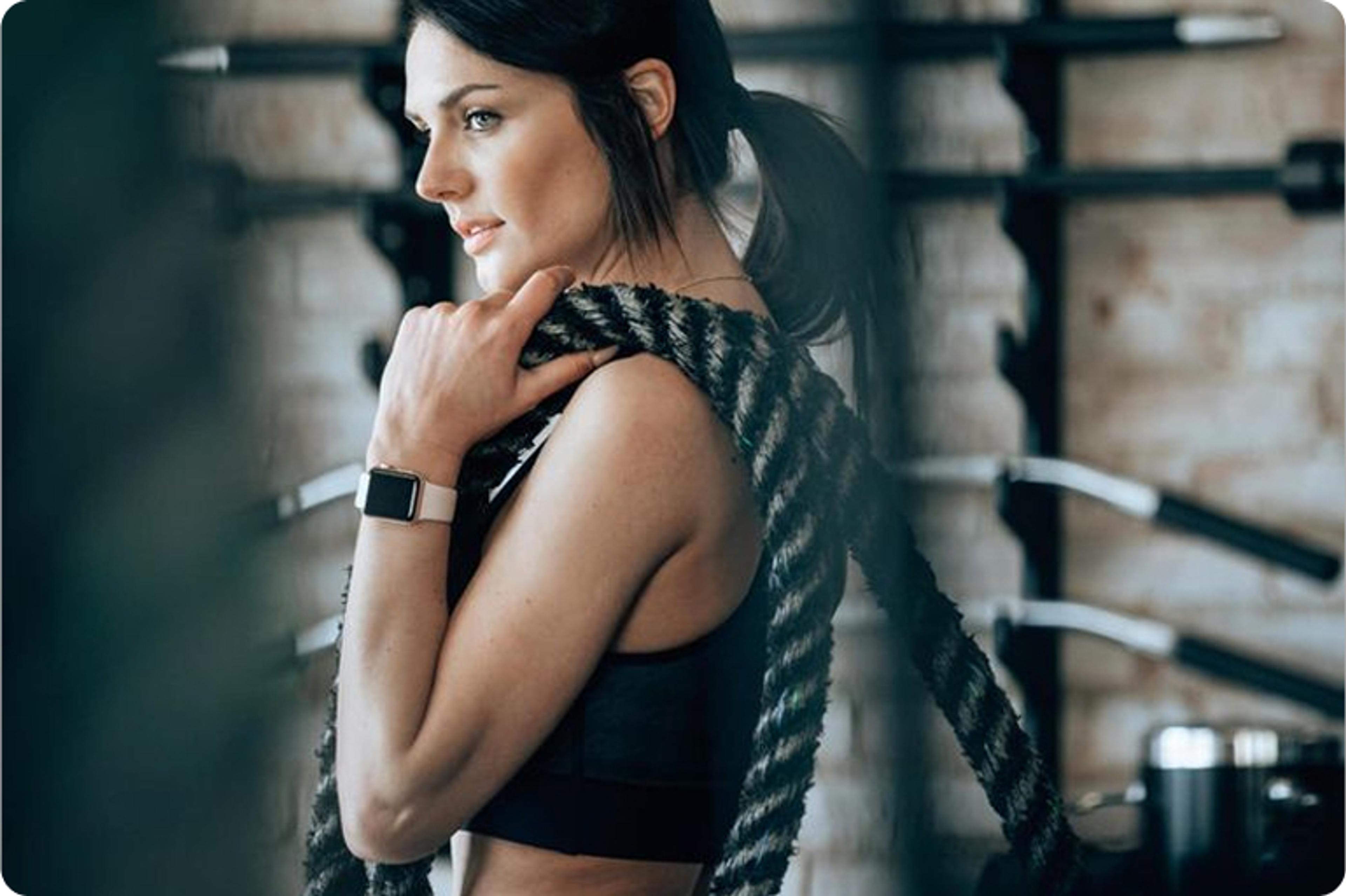 Eine Frau im Fitnessstudio, die Battle Ropes für ein intensives Training verwendet